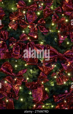 Christmas background - fir branches decorated with red bows and illuminated lights. Stock Photo