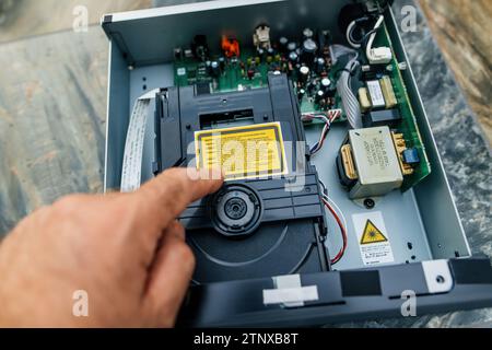 Munich, Germany - Sep 11, 2023: Open lid of the Onkyo C-755 CD Player with laser reading mechanism, hand pointing to a warning message Stock Photo