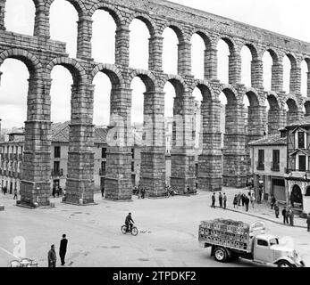 03/31/1961. THE TYPICAL AZOGUEJO UNDER THE IMPRESSIVE THEORY OF THE AQUEDUCT. PHOTO: RÍO.-.-In the photo you can also see the façade of the famous 'Casa Cándido Restaurant' next to the Aqueduct.- It is possibly the best and most complete aqueduct that remains of all those that were built in the Roman Empire, no only for its excellent conservation, but also for its concept, size and design. It has suffered some partial destruction, remodeling and even the partial disappearance of ashlars, specifically cornices. The grandeur, harmony and integration that the work brings to the city's landscape h Stock Photo