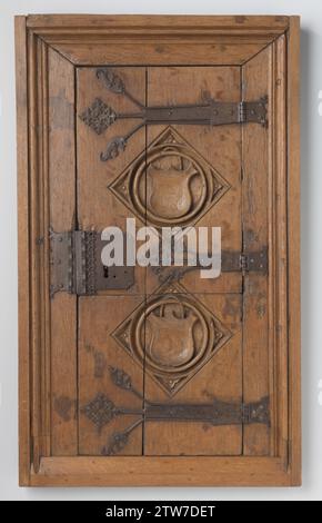 Door of a wall cupboard decorated with two windows inserted in relief, in which coats of arms, anonymous, 1500 - 1550 Door of a wall cupboard made of oak, attached in a profiled window with three tail stencies and decorated with two windows inserted in relief, within which coats of arms. The door consists of two widths and is cut through horizontally. The lock plate is at the height of the middle handle. The batter is partially decorated with engraving and ponslag. The corner sheets of the lock plate and perhaps also of the handles are missing, as well as the draft ring. Netherlands wood (plan Stock Photo