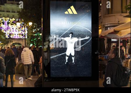 Madrid, Spain. 9th Dec, 2023. Pedestrians walk past a street commercial advertisement poster from Adidas featuring the Real Madrid football team and British professional footballer Jude Bellingham in Madrid. (Credit Image: © Xavi Lopez/SOPA Images via ZUMA Press Wire) EDITORIAL USAGE ONLY! Not for Commercial USAGE! Stock Photo