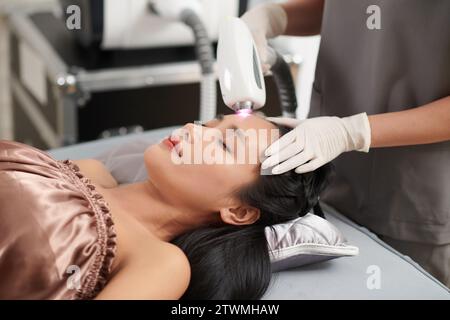 Woman getting forehead hair removal with alexandrite laser Stock Photo