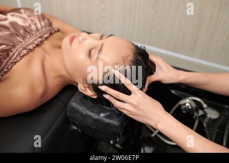 Hairdresser washing hair of client with deep cleaning shampoo to remove excess buildup Stock Photo