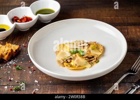 Italian dish ravioli with mushrooms and parmesan on wooden table Stock Photo