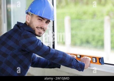 happy young man using spirit level on wall Stock Photo