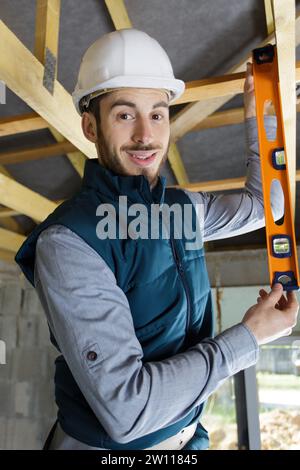 young male carpenter using spirit level on wooden beam Stock Photo