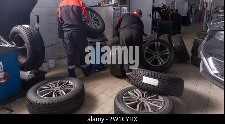Working inside tire service center. Replacing rubber on car wheels. Wheel balancing. Car tire service center auto repair workshop. Stock Photo