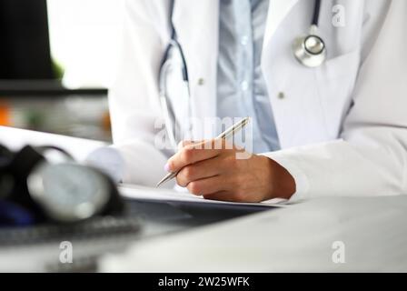 Hands of female GP making notes with silver pen Stock Photo