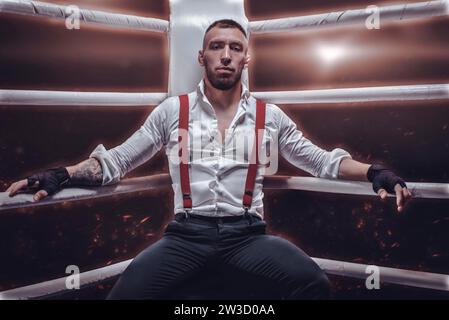 Image of a brutal man sitting in the corner of the ring. He looks defiantly at his opponent. The concept of fist fights. Mixed media Stock Photo