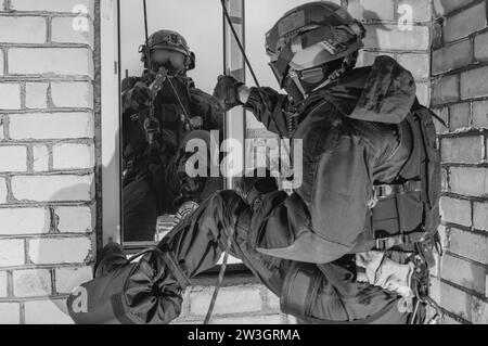 Group of special forces fighters storm the building through the window. Training sessions of the SWAT team. Anti-terror concept. Climbers. Mixed media Stock Photo