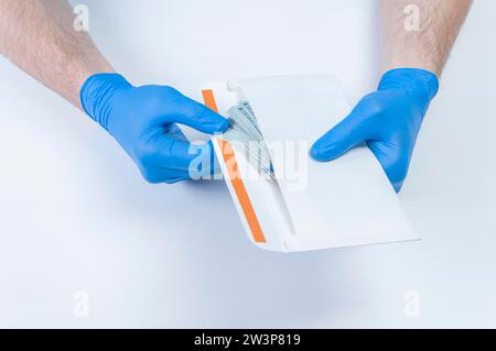 Image of hands in medical gloves holding an envelope with dollars. The concept of corruption in medicine. Mixed media Stock Photo
