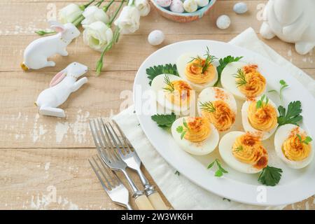 Easter stuffed eggs. Traditional Easter brunch or dinner with stuffed eggs with paprika, carrot cake bars and chocolate nest cakes with glazed eggs. E Stock Photo
