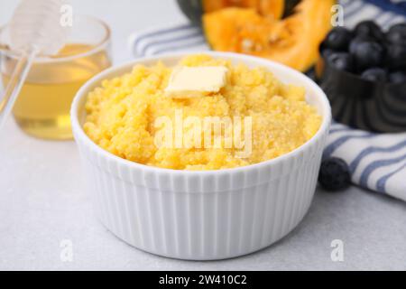 Tasty cornmeal with butter in bowl on light gray table, closeup Stock Photo