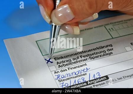 Eine Frauenhand Hand mit Kugelschreiber füllt das Formular zur Einkommensteuererklärung für das Finanzamt aus Stock Photo