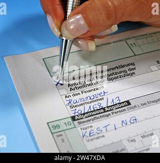 Eine Frauenhand Hand mit Kugelschreiber füllt das Formular zur Einkommensteuererklärung für das Finanzamt aus Stock Photo