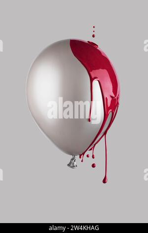 Red paint drips on grey balloon floating in the air. Minimalistic trendy concept. Stock Photo