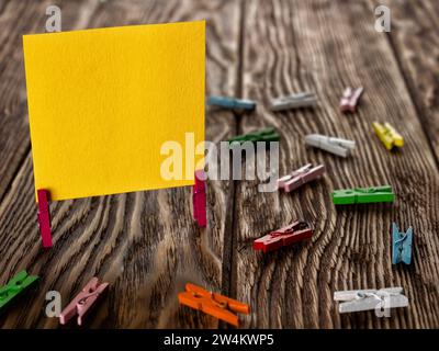 Blank yellow paper stand on wooden clothespins on wooden backround. Copy space for text or your image. Stock Photo
