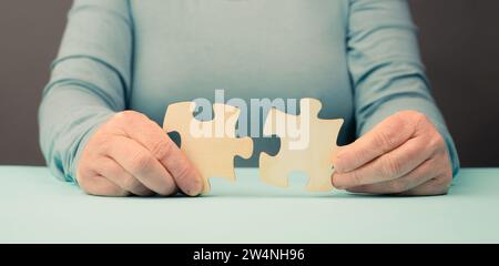 Holding two pieces of a puzzle in the hands, connecting together as a team, solving a problem, strategy and communication concept Stock Photo