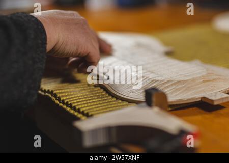 Unrecognizable luthier lute maker artisan hands in his workshop push and glue fillet purfling strips into carved inlaid wood channel, for a new raw Stock Photo