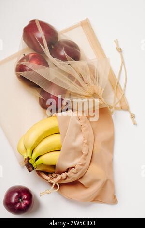Red apples and bananas in reusable bags. Stock Photo