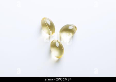 Three soft gel capsules, from above. Oral dosage medicine or dietary supplement in the form of a transparent capsule. Stock Photo