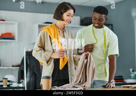 multiethnic designers with fabric samples and measuring tape working in print studio, small business Stock Photo