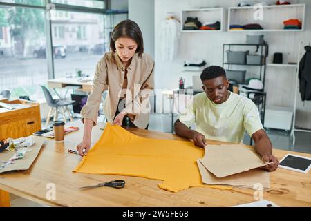 creative multiethnic fashion designers working with sewing patterns in print studio, small business Stock Photo