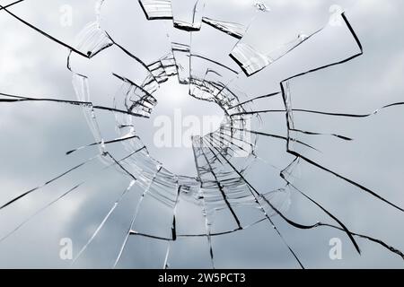 Broken window glass on a background of cloudy sky. Texture of broken glass for background. Close up. Stock Photo