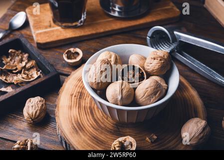 Walnuts in bowl and nutcracker on rustic table Stock Photo