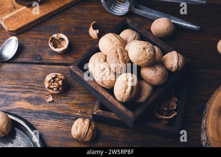 Walnuts in small wooden box and nutcracker on rustic table Stock Photo