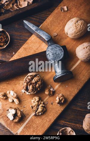 Cracked walnuts and hammer on cutting board Stock Photo