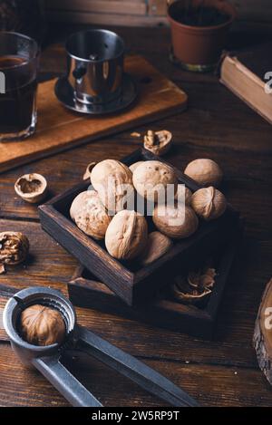 Walnuts in small wooden box and nutcracker on rustic surface Stock Photo