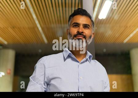 From below portrait of confident businessman dressed in light blue shirt and looking forward while standing in workplace Stock Photo