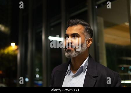 Side view of confident businessman dressed in suit and looking away while standing in workplace Stock Photo