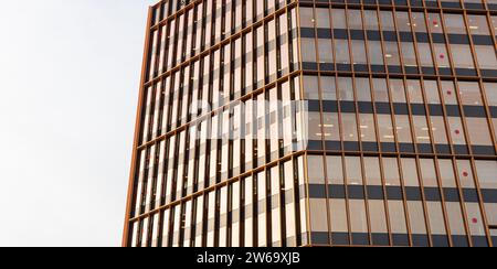 Close-up of a modern skyscraper's facade featuring reflective glass windows with golden metal frames against a clear sky. Stock Photo