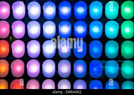 Abstract array of bright snapbacks with glowing multicolored LED light bulbs glowing against dark background in New York city Stock Photo