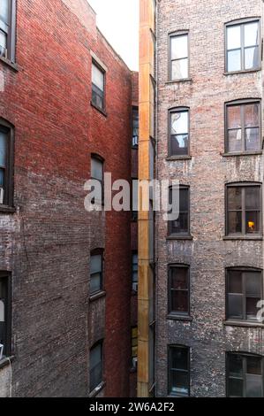 A narrow alleyway between old brick buildings with multiple windows and air conditioning units in Manhattan, New York. Stock Photo