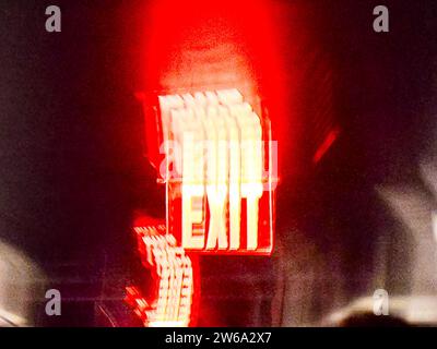 Blurry illuminated glowing bright red EXIT neon sign on building facade at dark night in New York city Stock Photo