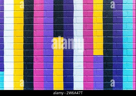 Colorful brick wall painted in various shades of pink, blue, purple, yellow, and black. Stock Photo