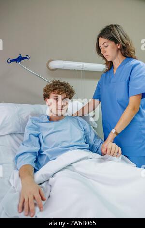 Young female doctor checking patient sitting on bed in hospital while working at clinic Stock Photo