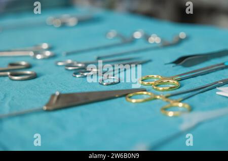 From above of various metal scissors and tools placed on blue table in modern clinic against blurred background Stock Photo