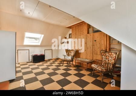 Table and empty chairs on tiled floor in furnished attic room of modern home with closet and skylight Stock Photo