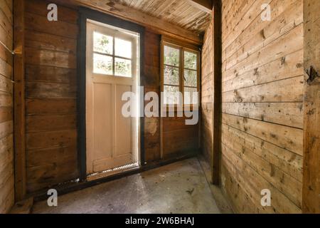 Closed white front door in small foyer of contemporary house with brown wooden walls and window Stock Photo