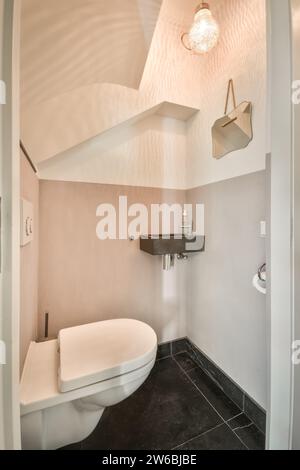Interior of illuminated light bulb hanging over toilet bowl with sink and mirror in restroom Stock Photo