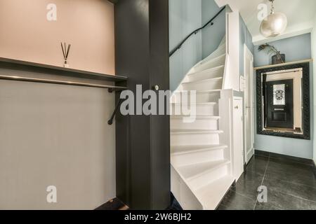 White staircase with mirror reflecting entrance door by light hanging in hallway of modern home Stock Photo