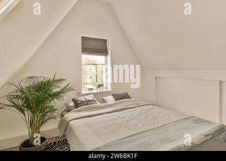 Planter by bed with cushions and pillows with blanket beside animal figurines on window sill at villa Stock Photo