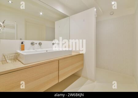 A sleek, modern bathroom featuring a wooden vanity with a large mirror, white sink, and minimalistic decor. Stock Photo