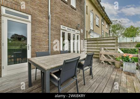 Dining table and chairs on wooden floor in cozy patio of modern house with glass door and brick wall Stock Photo