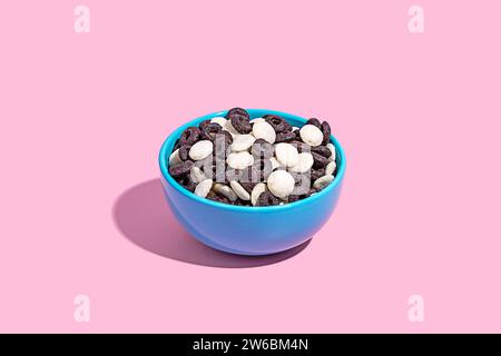 A blue bowl filled with a variety of chocolate candies captured against a soft pink background, perfect for confectionery themes. Stock Photo