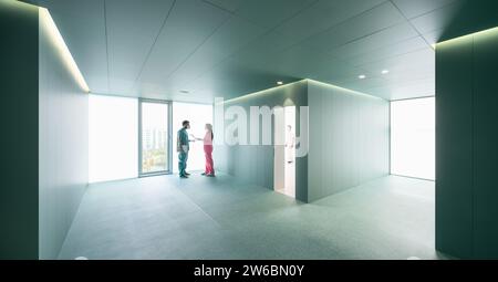 Full body of female nurse in pink uniform discussing with male surgeon in spacious green hall at modern hospital Stock Photo